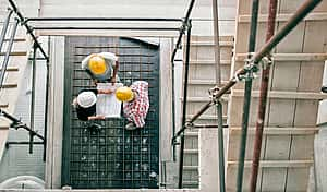 young trade workers discussing plans of tool leasing with Allan Gap Trust on clean construction sight with hard hats on